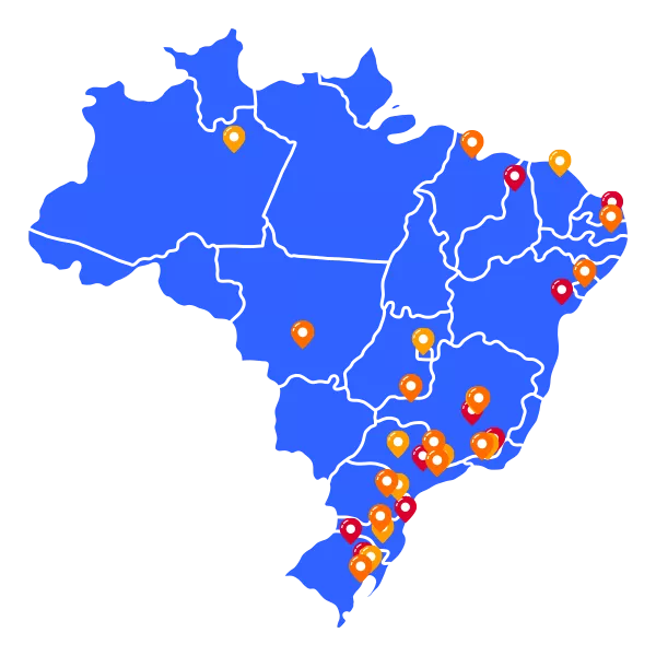 A modern and spacious lobby with large glass windows allowing natural light to flood the area. Hanging spherical lights in hues of orange and black add a contemporary feel. Sleek furnishings include a curved wooden bench and grey lounge chairs surrounding a small table. The space has a polished stone floor and an elegant reception desk near a staircase with glass railings.